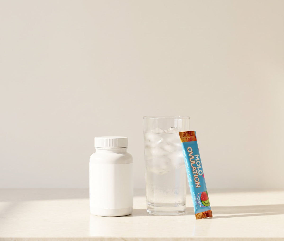 A plain prenatal bottle beside a glass of ice water with a Molo Ovulation stick leaning on it